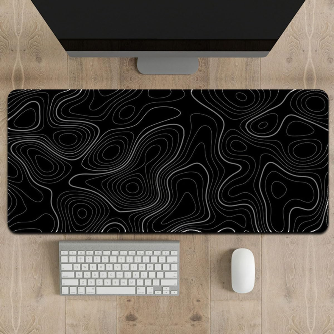 Black and white patterned desk mat on a wooden desk with a computer monitor, keyboard, and mouse.